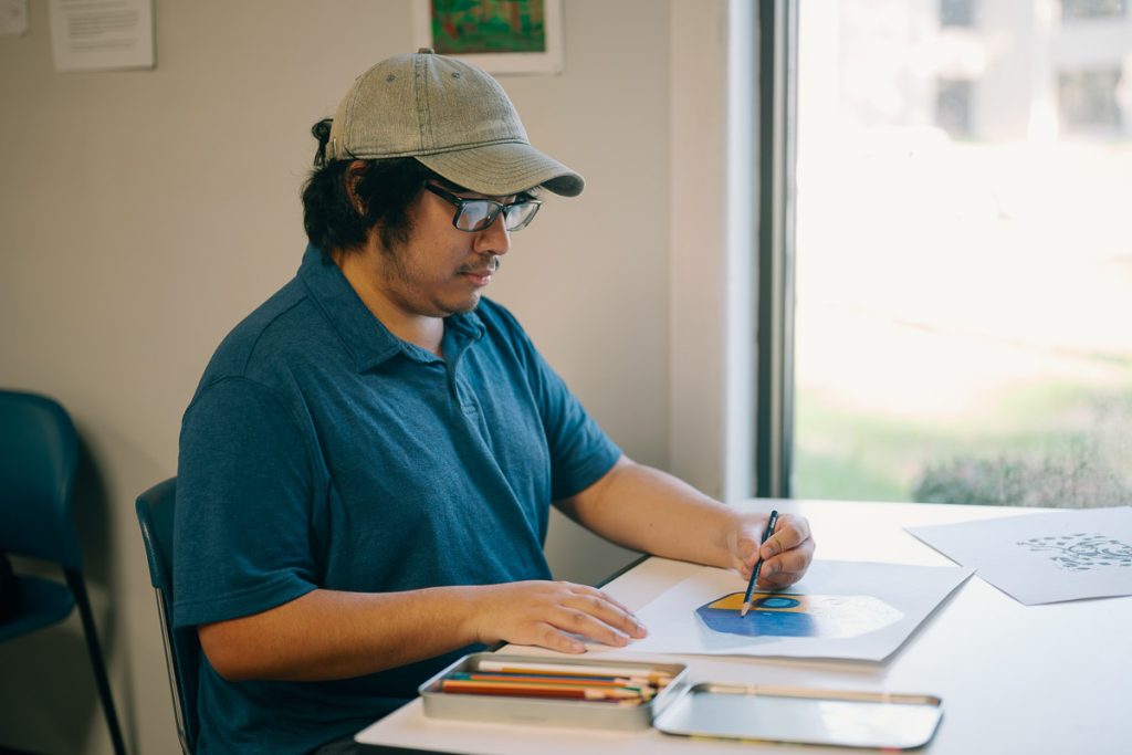 UMO Graphic Design student sketching artwork at desk