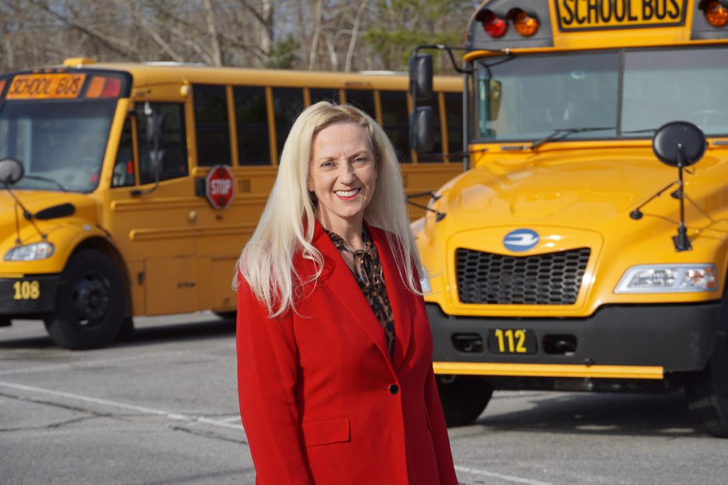Woman standing in front of school buses.