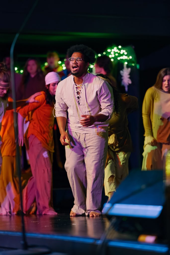 Chorus member portraying biblical character singing on stage.