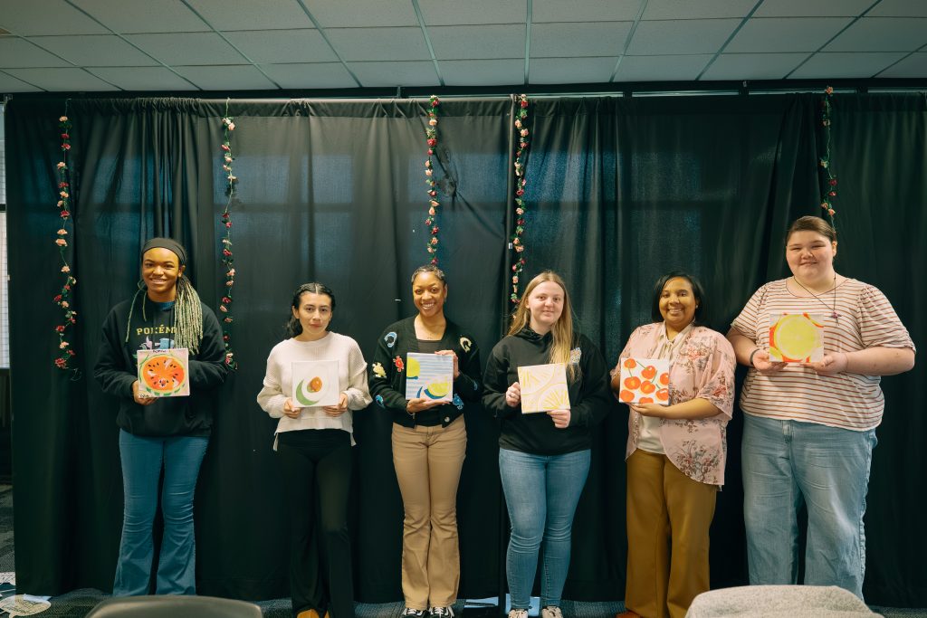 Group of scholarship recipients holding up their painted canvases.