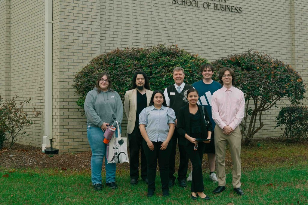 Group of UMO students and faculty standing outside the school's business building.