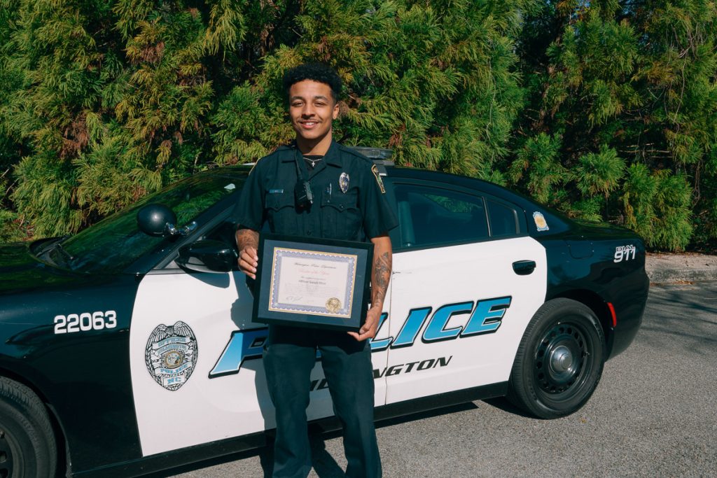 UMO Alumnus standing outside of his police car with his Rookie of the Year award.