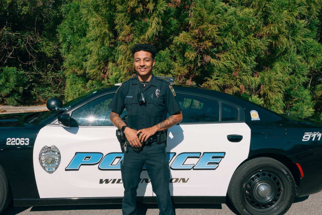 UMO Alumnus standing in front of his police car.